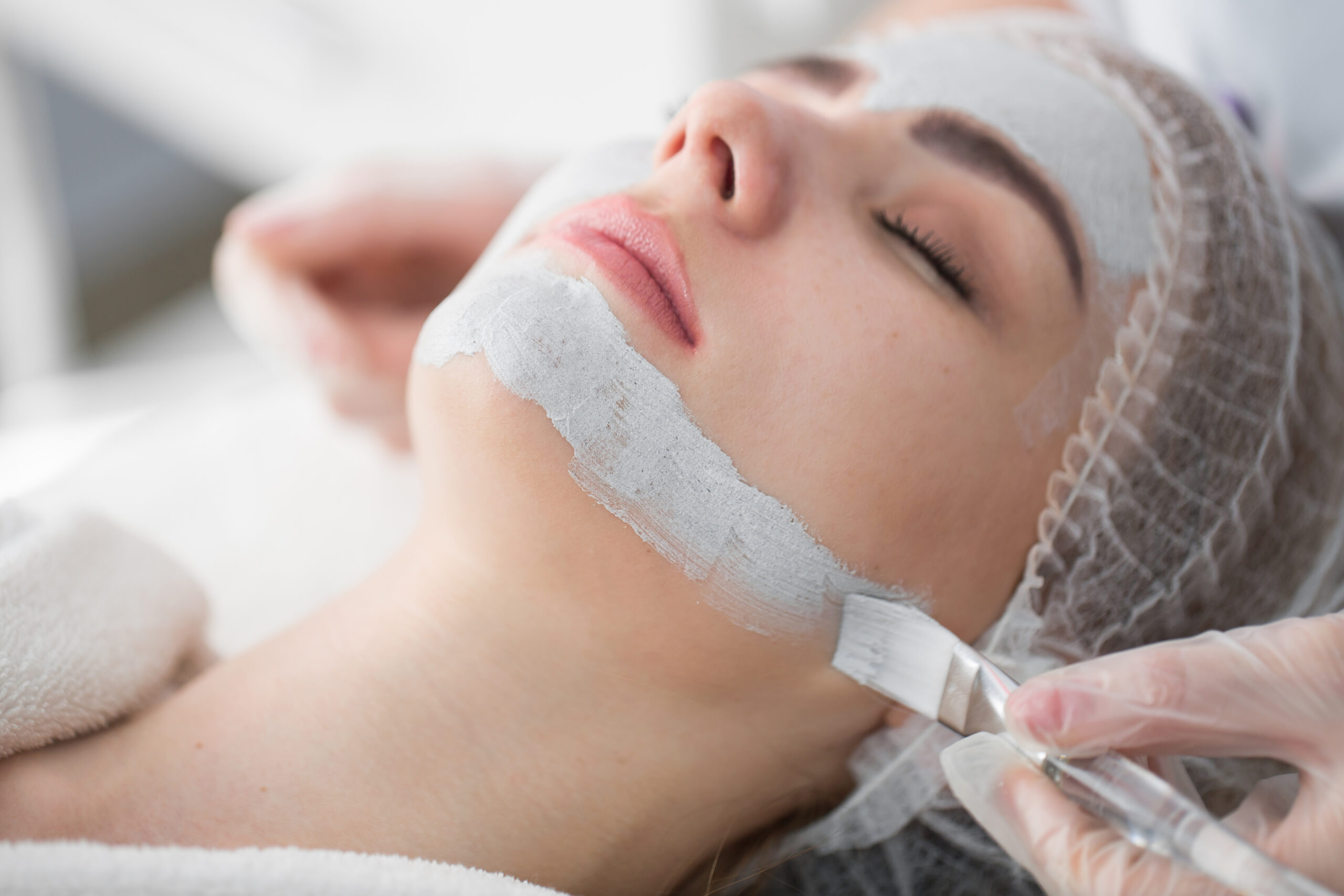 Face peeling mask, spa beauty treatment, skincare. Woman getting facial care by beautician at spa salon.